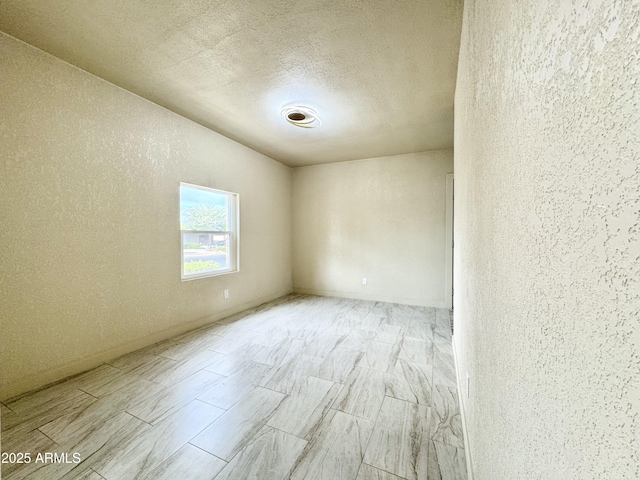 spare room with a textured ceiling, wood finish floors, and a textured wall