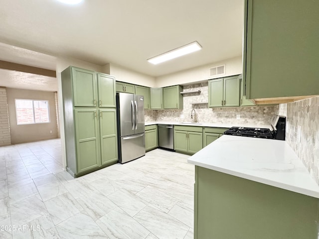 kitchen with a sink, stainless steel appliances, visible vents, green cabinets, and backsplash