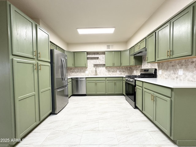 kitchen with a sink, green cabinetry, under cabinet range hood, appliances with stainless steel finishes, and marble finish floor