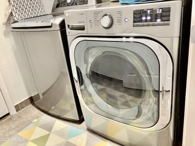 clothes washing area featuring separate washer and dryer and light tile patterned flooring