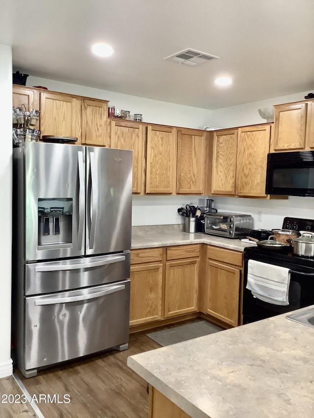 kitchen featuring dark hardwood / wood-style flooring and black appliances