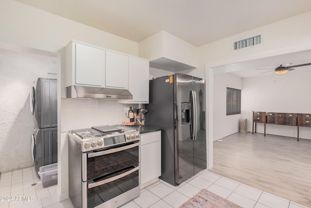 kitchen with white cabinetry, stacked washer and clothes dryer, stainless steel appliances, light wood-type flooring, and ceiling fan