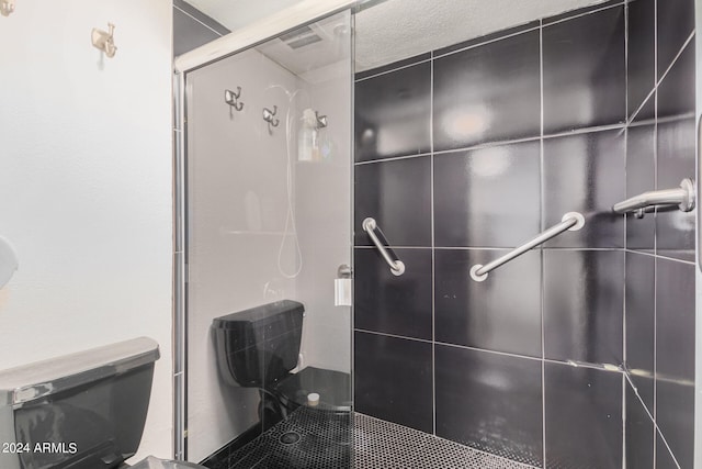 bathroom featuring a textured ceiling, a shower with door, and toilet