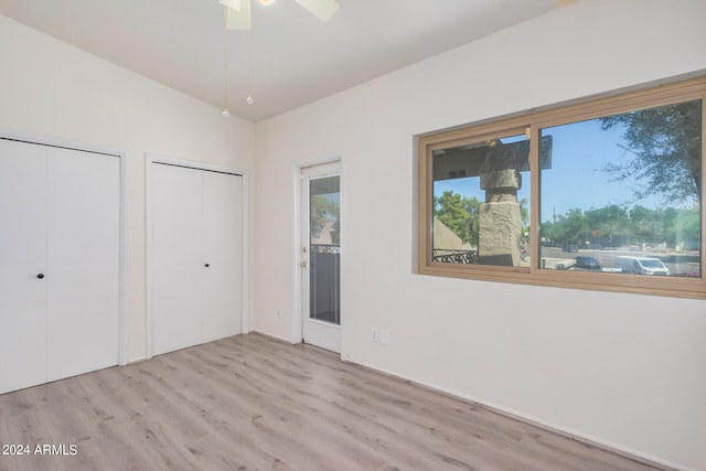 unfurnished bedroom with light hardwood / wood-style floors, two closets, lofted ceiling, and ceiling fan