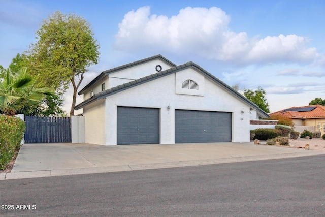 view of front of house with stucco siding, a gate, fence, concrete driveway, and a garage