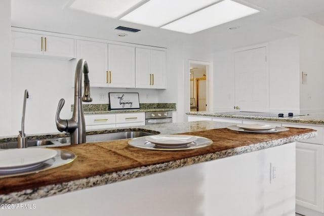 kitchen with visible vents, stone countertops, and white cabinetry