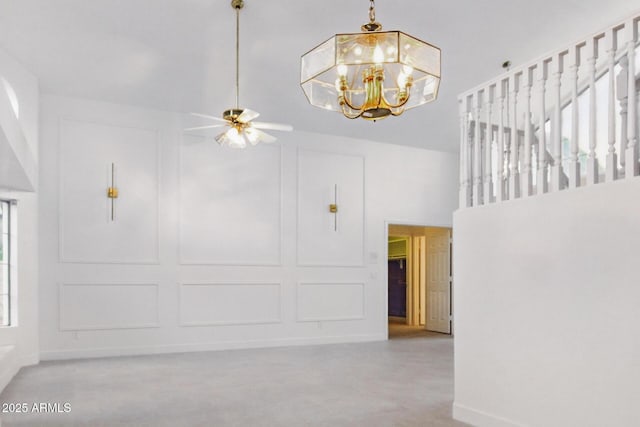 interior space with a decorative wall, ceiling fan with notable chandelier, a high ceiling, and baseboards