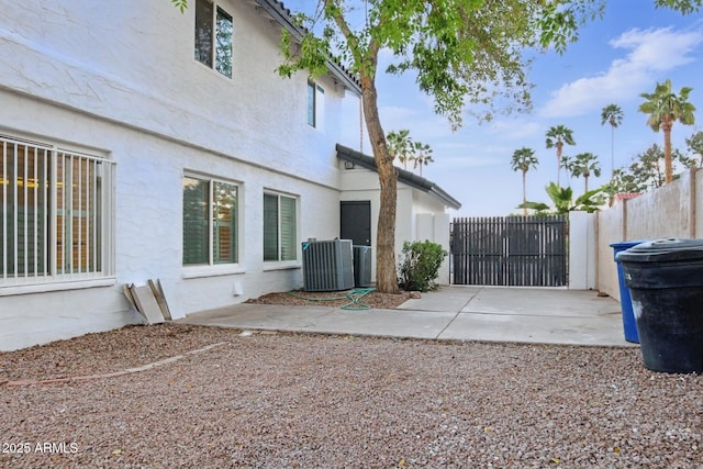view of property exterior with stucco siding, a patio, central AC, and fence