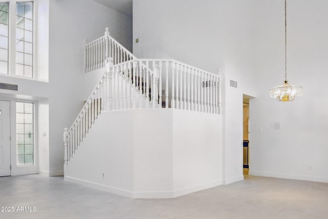 stairway with a notable chandelier, baseboards, a high ceiling, and visible vents