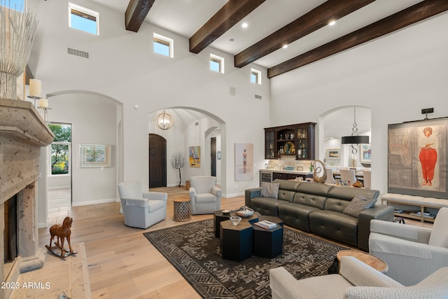 living room with light wood-type flooring, a towering ceiling, and beamed ceiling