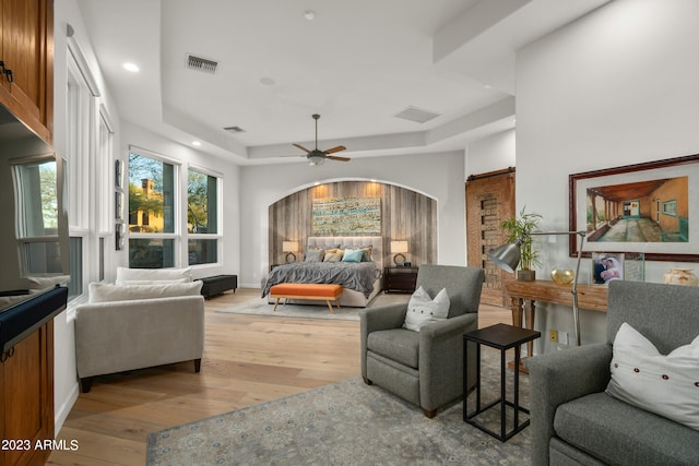 living room featuring a raised ceiling, light hardwood / wood-style floors, and ceiling fan