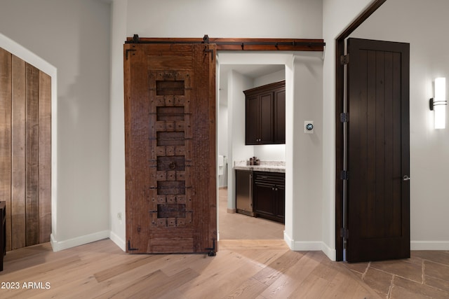 hallway with light wood-type flooring and a barn door