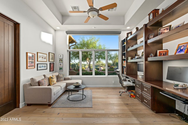 office featuring ceiling fan, light hardwood / wood-style flooring, built in desk, and a healthy amount of sunlight