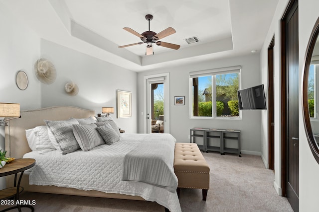 bedroom with a raised ceiling, access to outside, light carpet, and ceiling fan