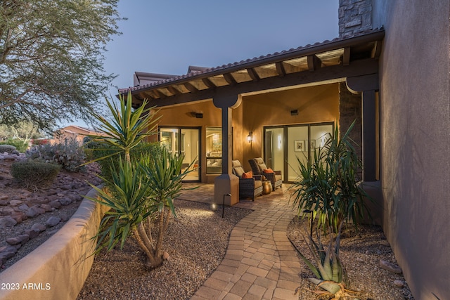 exterior entry at dusk with outdoor lounge area and a patio