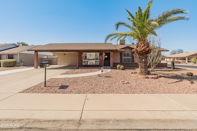 ranch-style home featuring brick siding, a carport, and concrete driveway