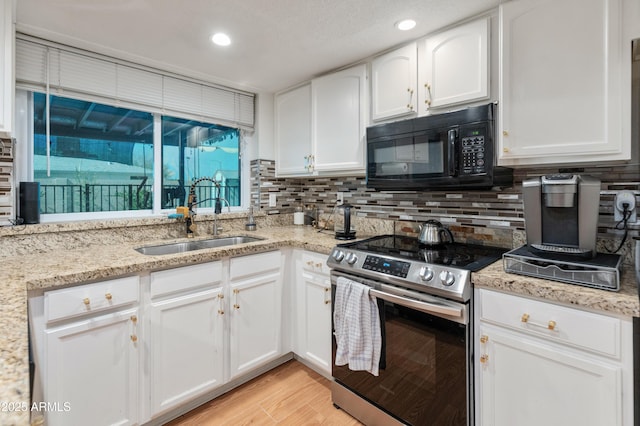 kitchen featuring electric range, black microwave, decorative backsplash, and a sink