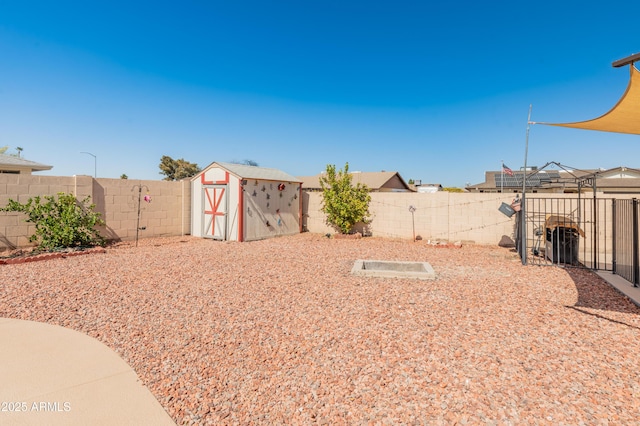 view of yard with a storage shed, a fenced backyard, and an outbuilding