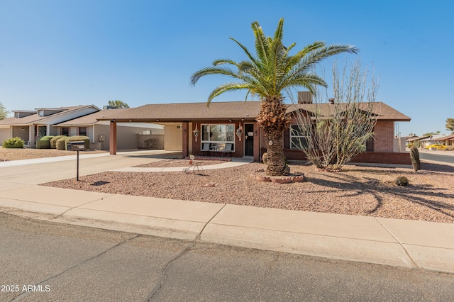 single story home featuring driveway, a carport, and brick siding