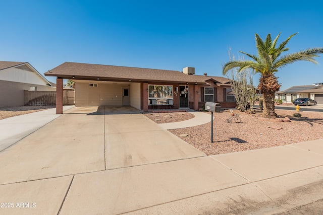 ranch-style house featuring driveway, fence, an attached carport, and central AC unit