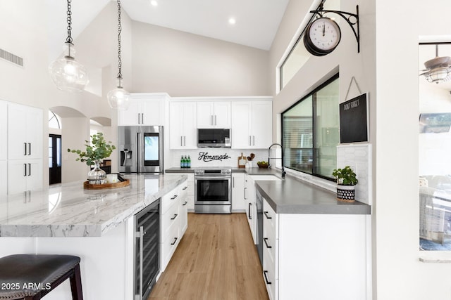 9821 E Windrose Dr, Scottsdale, AZ 85260 - kitchen with stainless steel appliances, wine cooler, high vaulted ceiling, backsplash, and white cabinets