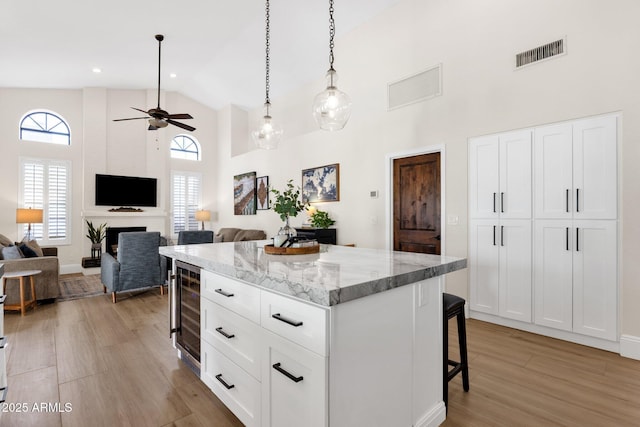 9821 E Windrose Dr, Scottsdale, AZ 85260 - kitchen featuring a breakfast bar, wine cooler, high vaulted ceiling, light wood finished floors, and a kitchen island