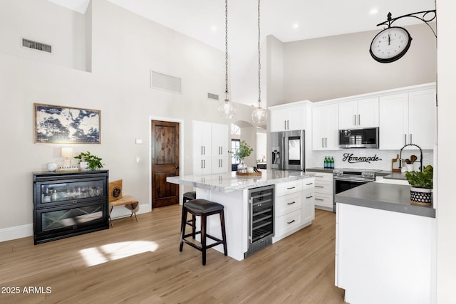 9821 E Windrose Dr, Scottsdale, AZ 85260 - kitchen featuring wine cooler, stainless steel appliances, high vaulted ceiling, a kitchen breakfast bar, and decorative backsplash