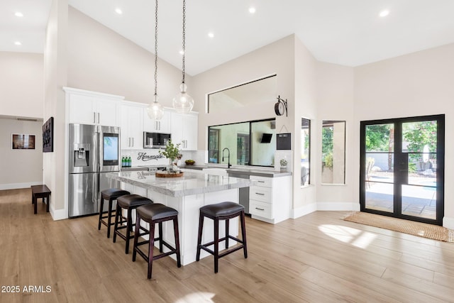 9821 E Windrose Dr, Scottsdale, AZ 85260 - kitchen featuring appliances with stainless steel finishes, high vaulted ceiling, a breakfast bar area, a center island, and light wood finished floors