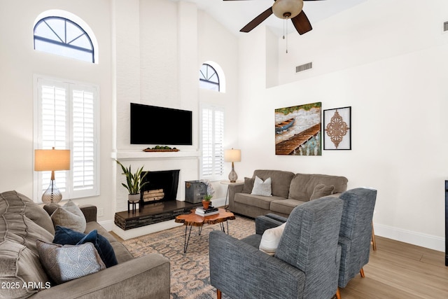 9821 E Windrose Dr, Scottsdale, AZ 85260 - living room with a ceiling fan, wood finished floors, a large fireplace, and high vaulted ceiling