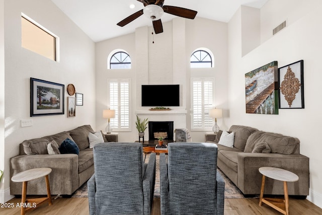 9821 E Windrose Dr, Scottsdale, AZ 85260 - living area featuring a ceiling fan, light wood finished floors, high vaulted ceiling, a fireplace, and healthy amount of natural light