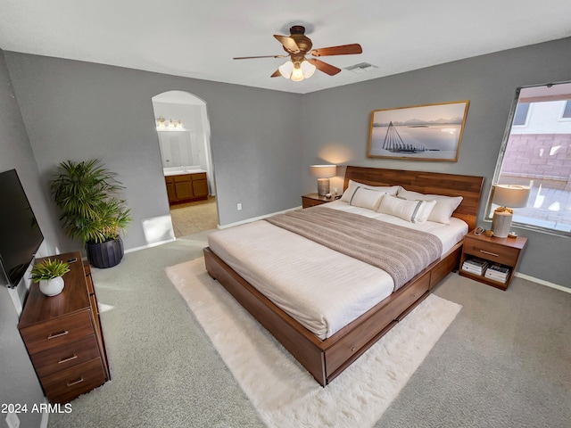 carpeted bedroom with ensuite bathroom and ceiling fan