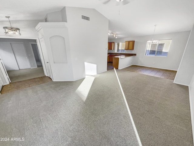 unfurnished living room with light carpet, ceiling fan with notable chandelier, and lofted ceiling