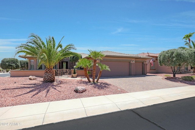 view of front of property featuring a garage, decorative driveway, a tile roof, and stucco siding