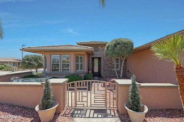 exterior space featuring stone siding, fence, a gate, and stucco siding