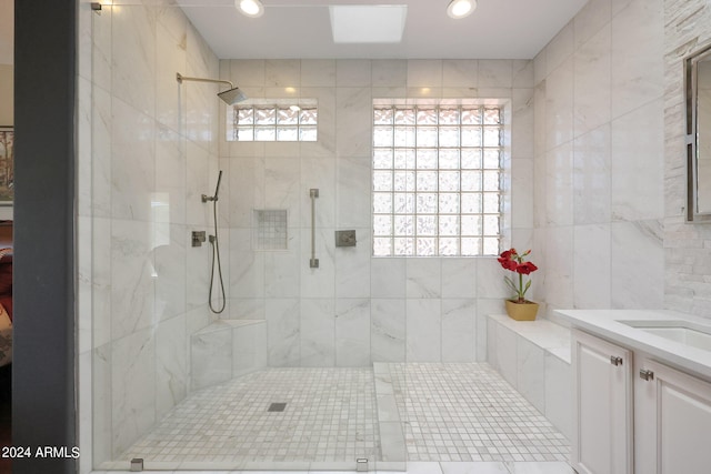 bathroom with tile walls, tiled shower, and vanity