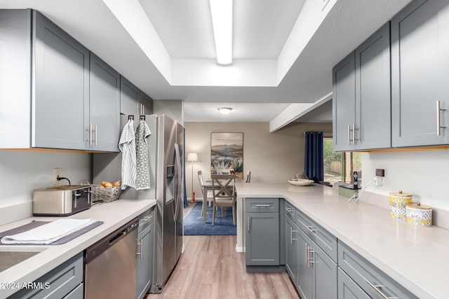 kitchen featuring gray cabinets, dishwasher, and light wood-type flooring