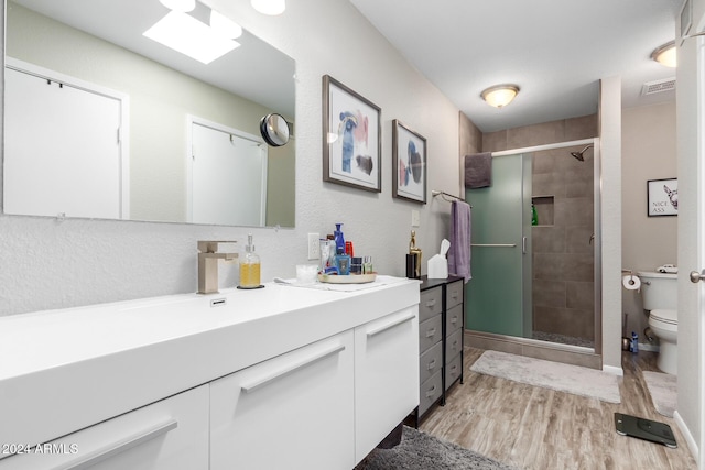 bathroom with walk in shower, wood-type flooring, toilet, and vanity