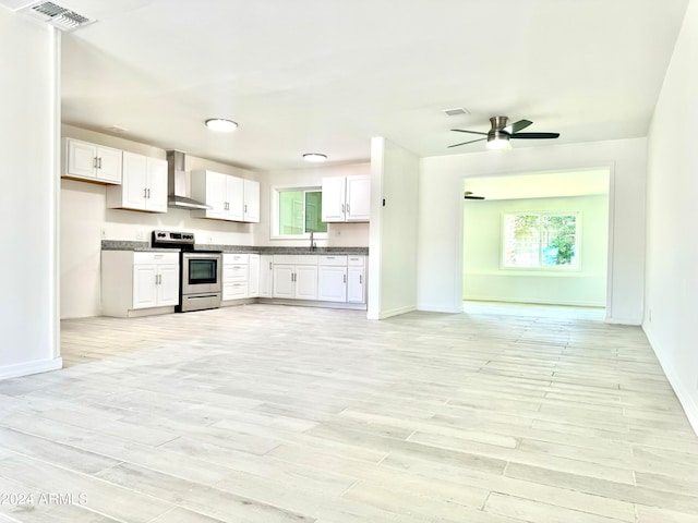 kitchen featuring light hardwood / wood-style flooring, white cabinetry, stainless steel electric stove, and wall chimney range hood