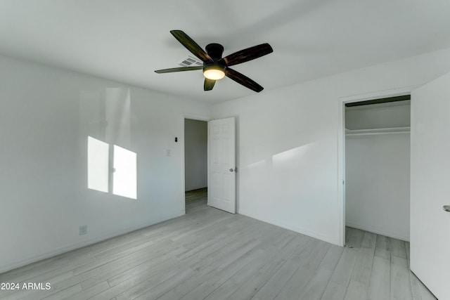 unfurnished bedroom featuring ceiling fan, light hardwood / wood-style floors, and a closet