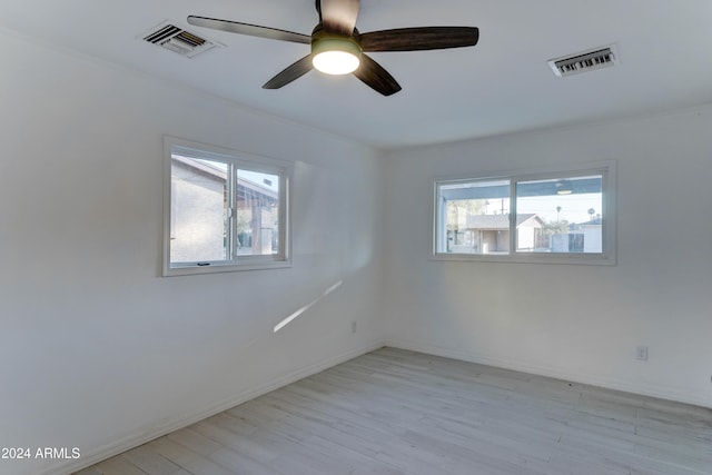 spare room featuring ceiling fan, light wood-type flooring, and a wealth of natural light