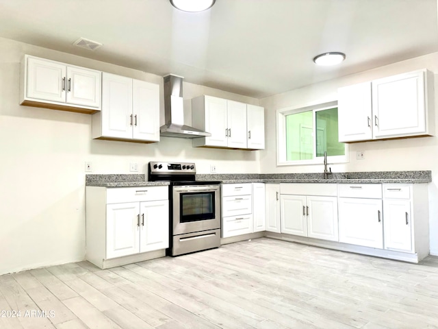 kitchen with white cabinetry, stainless steel electric range oven, wall chimney exhaust hood, and light hardwood / wood-style flooring