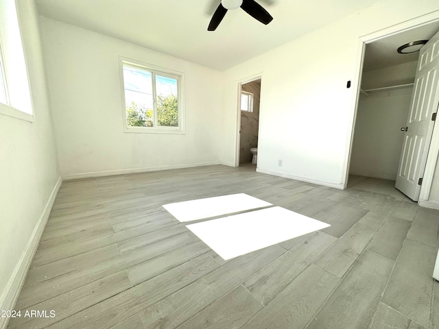 unfurnished bedroom with a closet, light hardwood / wood-style floors, ensuite bath, and ceiling fan