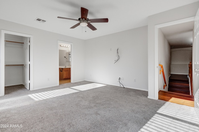 unfurnished bedroom featuring a spacious closet, light carpet, ceiling fan, and a closet