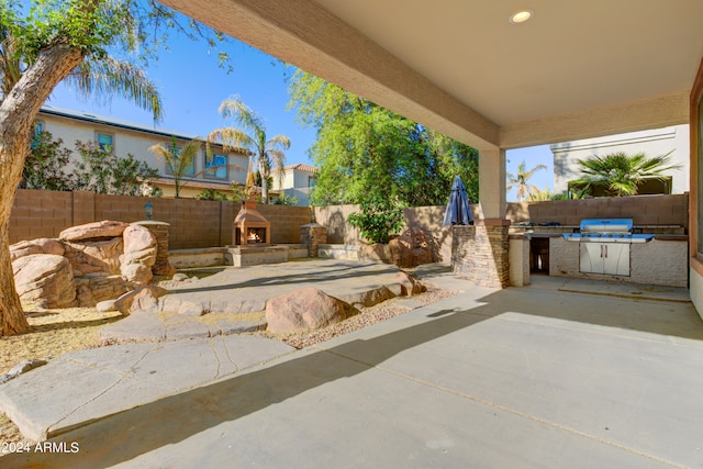 view of patio featuring an outdoor fireplace, exterior kitchen, and area for grilling