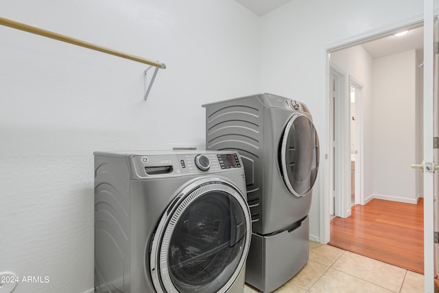 clothes washing area with light tile patterned floors and independent washer and dryer