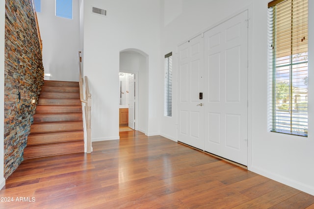 entrance foyer with hardwood / wood-style floors and a towering ceiling