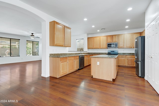 kitchen with stainless steel appliances, a kitchen island, dark hardwood / wood-style floors, and dark stone countertops