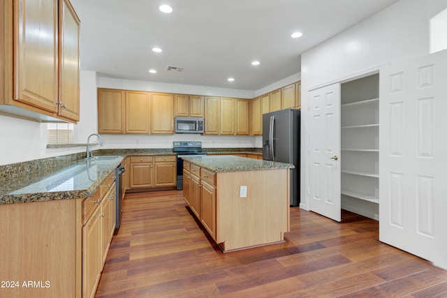 kitchen with sink, stone counters, appliances with stainless steel finishes, dark hardwood / wood-style floors, and a kitchen island