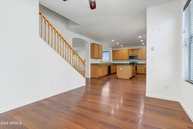 kitchen with a healthy amount of sunlight, dark wood-type flooring, a center island, and black dishwasher