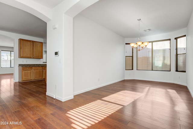 unfurnished dining area featuring dark wood-type flooring and a chandelier